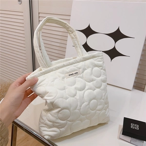 Detail of white quilted handbag with 3D flower pattern and simple wish label text