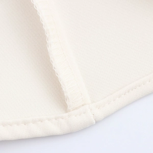 Macro view of beige knitted fabric showing detailed texture and precision stitching