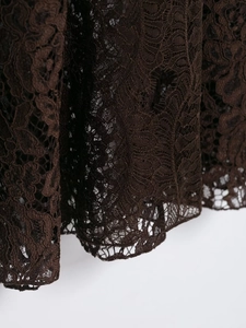 Detailed macro view of delicate dark brown lace hem with intricate floral patterns