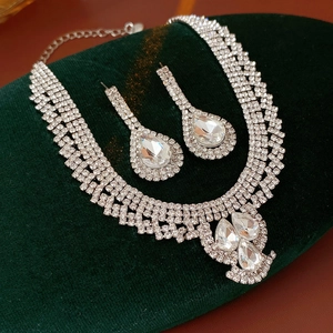Detailed view of silver water drop necklace and earrings set on green velvet pad