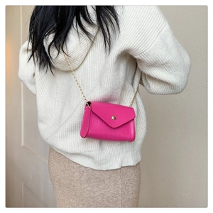 Rose red crocodile pattern small crossbody bag with gold chain strap on beige sweater