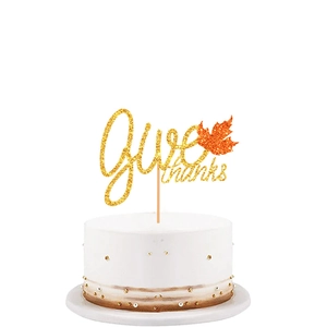 Macro detail of Give thanks gold glitter cake topper with orange maple leaf
