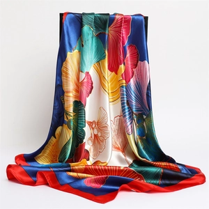 Detail of satin silk scarf featuring vibrant ginkgo leaves print on navy blue background