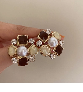 Close-up of vintage flower earrings with pearls and crystals held by hand