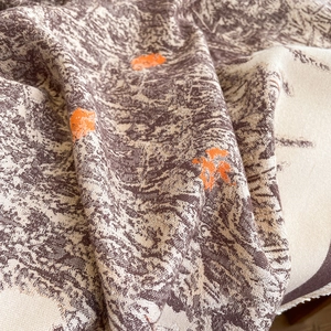 Close-up of thick winter scarf with orange daisy embroidery and soft fringe edge