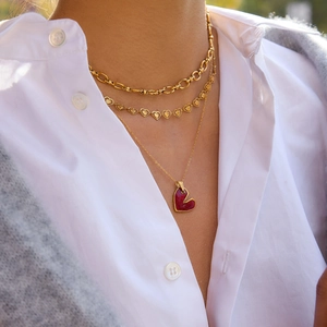 Primo piano di collane a strati placcate oro 18K con ciondoli a cuore in smalto rosso