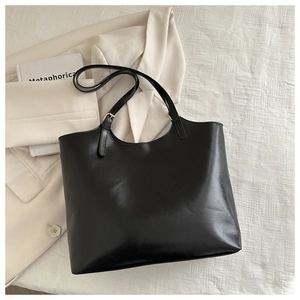 Nahaufnahme schwarzer Retro-Shopper mit goldener Schnalle und Büro-Deko-Accessoires