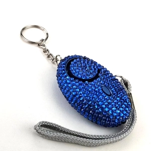 Close-up of blue rhinestone-studded personal safety alarm with wrist strap and keychain