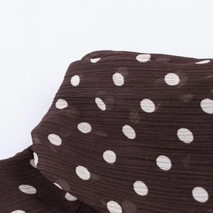 Detailed macro shot of dark brown polka dot fabric with pleated texture and chiffon feel