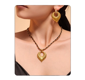 Detail of 18k gold-plated jewelry set with heart necklace and rhinestone earrings on model