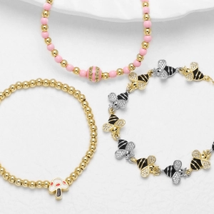 Three gold-plated bracelets featuring bees, mushrooms, and pink beads in a stylish set