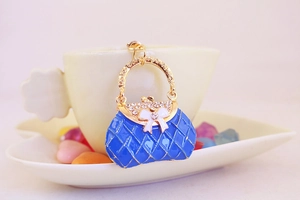 Close-up of a blue enamel handbag keychain with gold frame and sparkling rhinestones