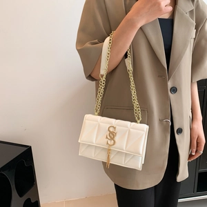 Chic white quilted crossbody bag with gold S-buckle and tassel on a stylish model