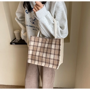 Detail of checkered canvas tote bag with woven texture and white knotted rope handles