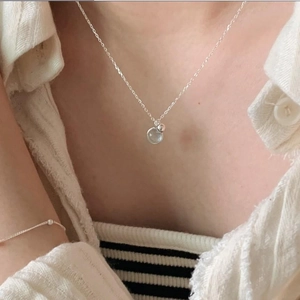 Detail of 925 sterling silver necklace with light blue round crystal on a female model