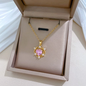 Detail of a gold heart necklace with a pink gemstone in a brown jewelry box