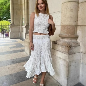 Détail d'un ensemble deux pièces en dentelle blanche avec haut sans manches et jupe sirène midi