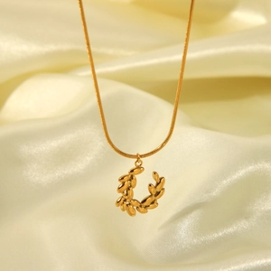 Golden leaf wreath pendant necklace on beige silk fabric with high-shine snake chain link