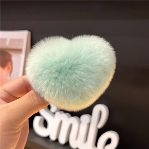 Close-up of light green heart-shaped rabbit fur clip showing its fluffy plush texture