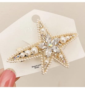 Close-up of star-shaped hair clip with sparkling rhinestones and white pearls