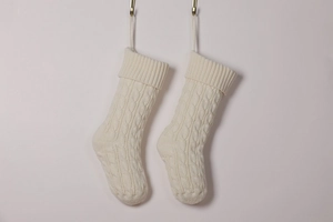 Detailed cable knit texture of ivory white Christmas stockings on light pink wall