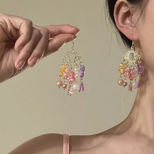 Detailed view of vintage gold hollow earrings with colorful hanging beaded tassels