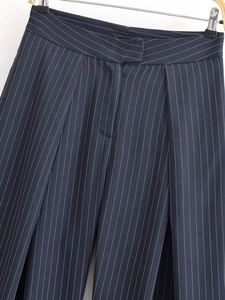 Gros plan détaillé montrant la taille haute plissée et la texture rayée du pantalon large