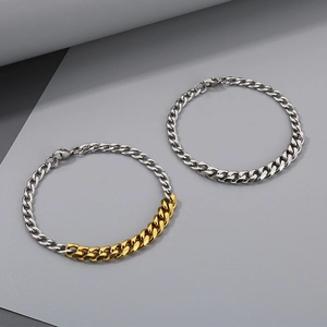 Detail view of silver and gold two-tone Cuban link chains with lobster clasps