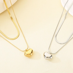 Detailed view of layered gold and silver snake chains with heart-shaped pendants
