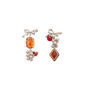 Vintage asymmetric silver bow earrings with amber resin and red beads on white backdrop