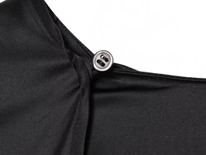 Close-up of a black silk cape top featuring detailed stitching and a single matching button