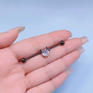 Piercing industrial in metallo nero con una pietra di zircone trasparente a forma di cuore