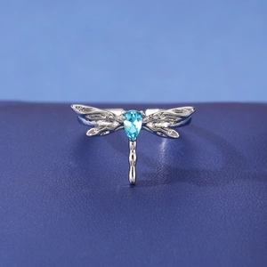Macro detail of silver dragonfly ring featuring a vibrant blue teardrop crystal inlay