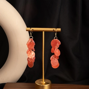 Detailed macro view of cascading amber resin bead earrings on a gold display stand