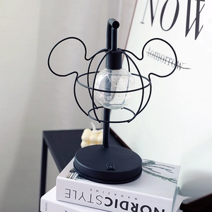 Minimalist Mickey mouse shaped LED table lamp with black metal frame on books