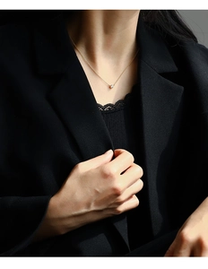 Detailed view of a gold round pendant necklace with a zircon stone worn on a model