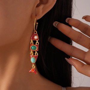 Detail view of colorful fish-shaped tassel earrings with enamel and gems worn by a model
