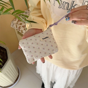 Quilted floral coin purse with purple wrist strap held by model for size reference