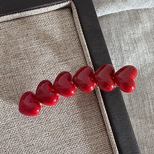 Macro shot of six red polished heart charms on a sleek duckbill hair clip detail