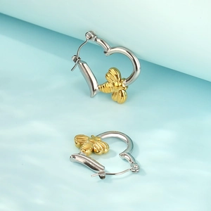 Macro shot of silver heart hoop earrings with detailed 3D gold bee charms