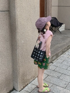 Detail of a child wearing a retro black woven crossbody bag with pink summer outfit