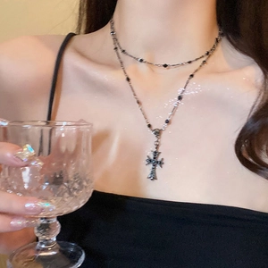 Détail du collier double couche avec pendentif croix et perles noires sur chaîne argent