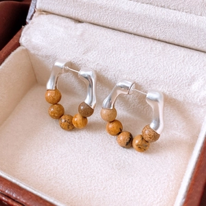Detailed close-up of retro stone beaded hoop earrings in a beige velvet jewelry box