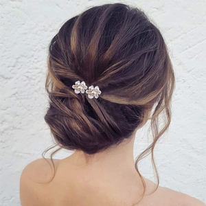 Détail d'épingles à cheveux fleurs en perles et strass sur une coiffure de mariée élégante