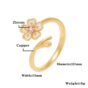 Detail of cherry blossom ring with white enamel petals and pink zircon on a golden band