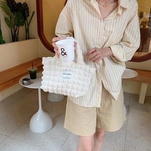 Detail view of cream textured bubble tote bag with Love Sozakka label in a cafe setting