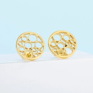 Macro shot of minimalist hollow circular gold stud earrings on light blue backdrop