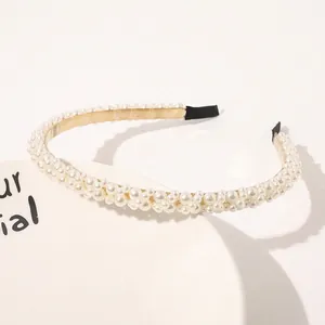 Detail of elegant gold metal headband with various white faux pearls and black ear pads