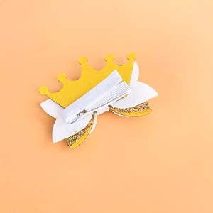 Detail of glitter bow hair clip with yellow crown and protective fabric wrapped clip