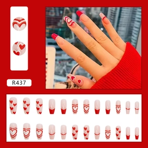 Dettaglio di unghie finte rosse e bianche con cuori e layout completo da 24 pezzi